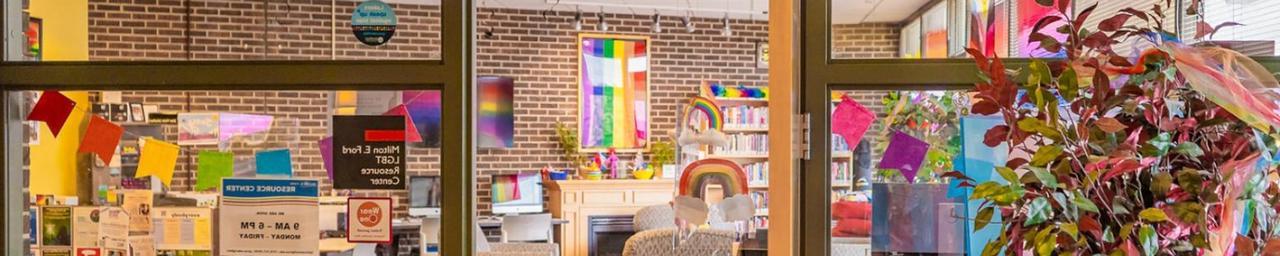 透过LGBT资源中心的门和玻璃窗. 它的内部是明亮多彩的，有一个可见的彩虹旗. 图片来源:Macayla与Lanthorn 2022